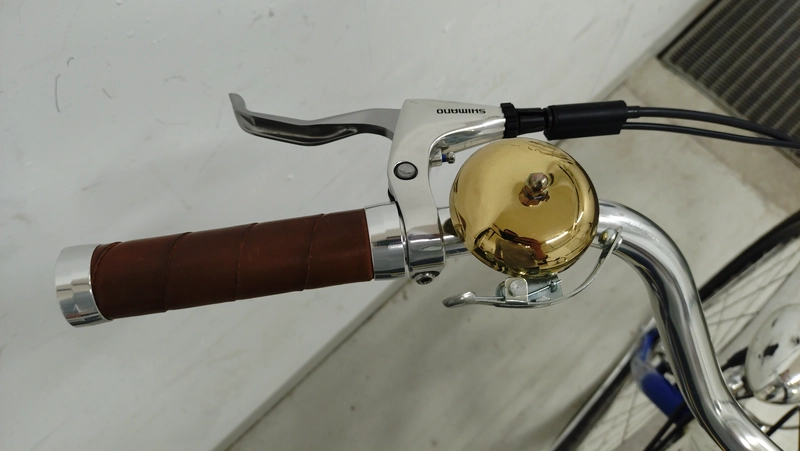 The cockpit of my ebike, showing the handlebars, bell, brake levers and grips